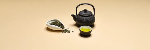 small pile of mecha tea showing its distinctive compact, rounded bud shapes beside a brewed cup of pale yellow-green liquor, representing this bold Japanese green tea made from young sencha and gyokuro buds.