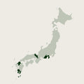 A minimalist map of Japan on a light beige background, with the main island highlighted in pale sage green and several smaller surrounding islands highlighted in dark green.